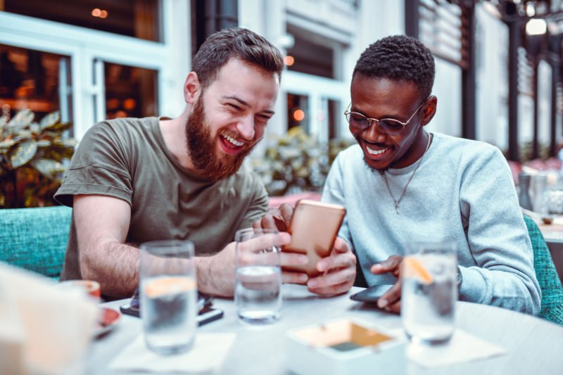 Swedish-Male-Laughing-While-Browsing-Social-Media-With-His-African-Friend-1184006408_8256x5504-800x533