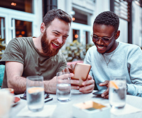 Swedish-Male-Laughing-While-Browsing-Social-Media-With-His-African-Friend-1184006408_8256x5504-800x533