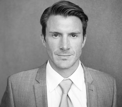 Black and white headshot portrait of a professional businessman in a suit.